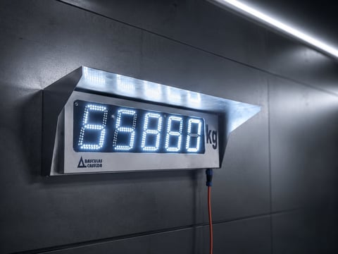 Digital display scale mounted on wall showing weight reading of 59860 kg with LED readout and red power cable